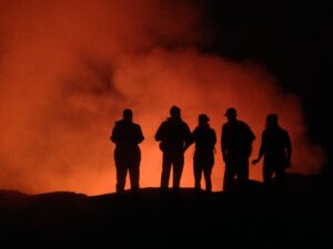 Dancers standing at the edge of a crater of lava.